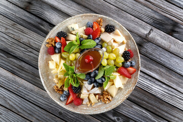 Cheese platter: variety of cheeses on wooden plate with fruits, nuts and berries.