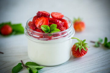 Sweet homemade yogurt with fresh ripe strawberries in a glass jar