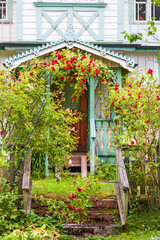 Obraz premium Red roses in a garden with an old cottage