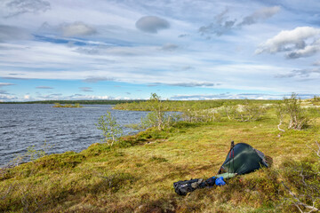 Fototapeta na wymiar Hiking tent at a lakeshore in the wilderness