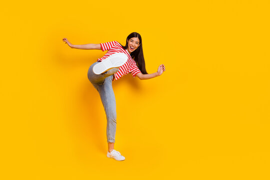 Full body photo of positive overjoyed person have fun raise leg kick isolated on yellow color background