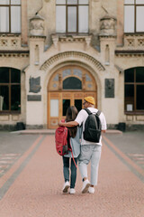 Fototapeta na wymiar International students couple walking to the university building hugging each other, wearing stylish clothes