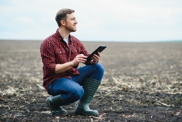 A farmer checks quality of soil before sowing. woman farmer with a tablet in field holds earth in his hands. girl agronomist checks the quality of sowing grain. business woman checks her field.