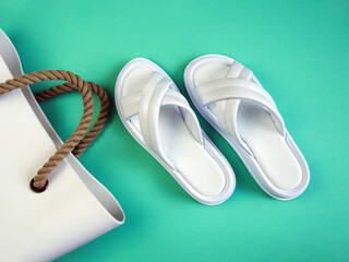 Women's summer white slippers and a white rubber bag with brown handles on a black background. Slippers. Horizontal image