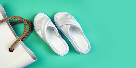 Women's summer white slippers and a white rubber bag with brown handles on a black background....