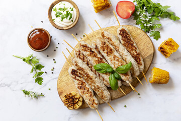 Summer party food. Grill food menu. Bbq grilled chicken kebab with fresh herbs and spices on marble tabletop. View from above.