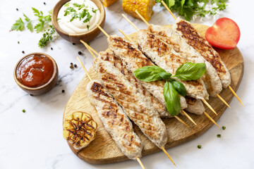 Summer party food. Grill food menu. Bbq grilled chicken kebab with fresh herbs and spices on marble tabletop.