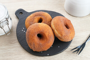 Donat Kentang (Potatoes Donut), donuts with added potato ingredients. Dusted with powdered chocolate and served on a small plate.
