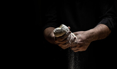 Hands of baker kneading dough isolated on black background. prepares ecologically natural pastries. place for text