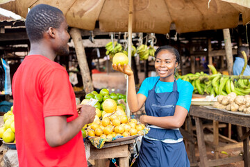 black female farmer selling fruit to a young man