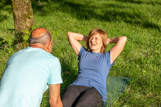 Close Up Protrait Of Two Older Men And Woman Exercising While Having Fun And Similing In The Park