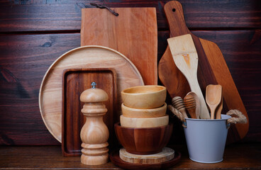 Wooden chopping boards, cups, trays, and kitchen utensils on a wooden table.