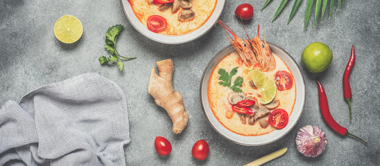 Tom yum kung Spicy Thai soup with shrimp in a bowl. Gray concrete background. Top view, flat lay. Toned image. Banner - obrazy, fototapety, plakaty