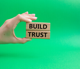 Build trust symbol. Wooden blocks with words Build trust. Beautiful green background. Businessman hand. Business and Build trust concept. Copy space.