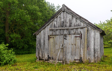 Looking across the green grass at an old black wooden barn building with closed doors