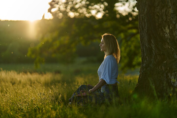 Young woman posing at sunset by an oak tree