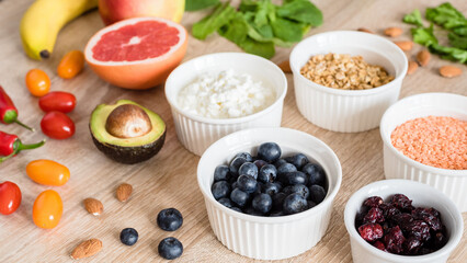 Fototapeta na wymiar Healthy food concept. Cottage cheese, fruits, vegetables, leaf vegetables, berries, dried fruits and nuts on a wooden table. clean food