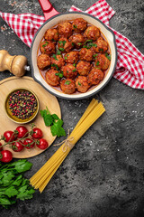 Meatballs with tomato sauce in frying pan on black background, vertical image. top view. place for text