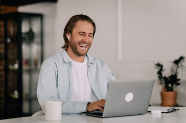 Handsome Man with Laptop at Home Listening to Webinar and Smiling
