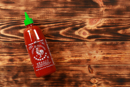 Bottle of Sriracha hot chili sauce on wooden background	