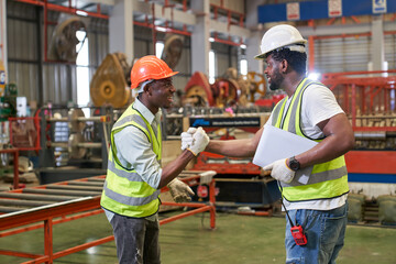 Two African American foreman happy and join strong shake hand to together in metal sheet factory