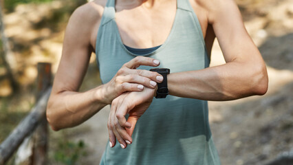 Cropped of young sports woman browsing smartwatch