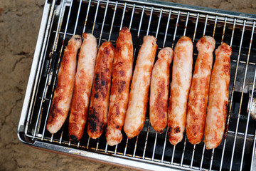 Sausages baked on a gas grill grate close-up top view. BBQ, picnic, barbecue food