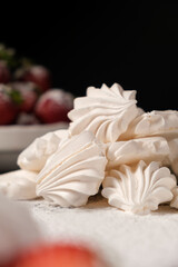 Meringue close up and strawberries in a plate on a black background. Fruit desserts.