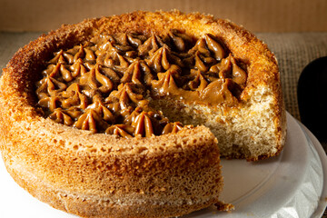 typical brazilian churros cake with dulce de leche, on a table with plates and coffee, comfortable breakfast or snack scene