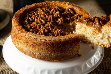 man hand cutting a slice of typical brazilian churros cake with dulce de leche, on a table, comfortable breakfast or snack scene