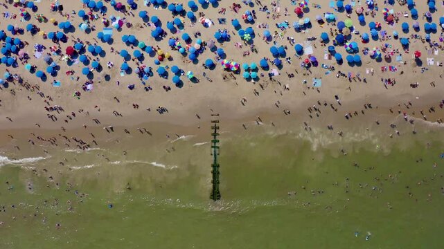 Drone video shows many people at beach and majority of them are with blue umbrella