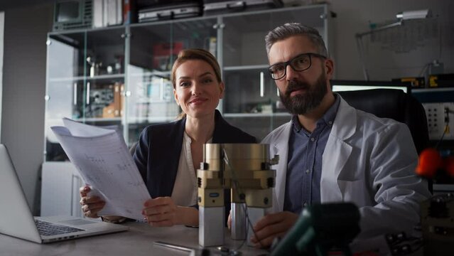 Robotics engineers working on laptop and desinging modern robotic arm in laboratory.