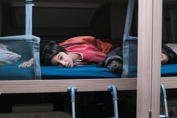 Girl waking up next to her black dog on her family caravan route
