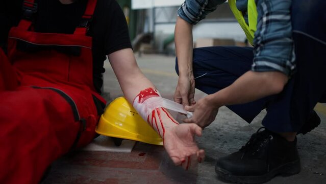 Woman is helping her colleague after accident in factory. First aid support on workplace concept.