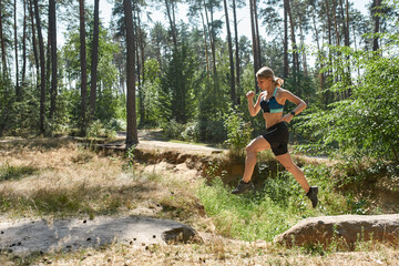 Fototapeta na wymiar Sportswoman jump over hole during run in forest