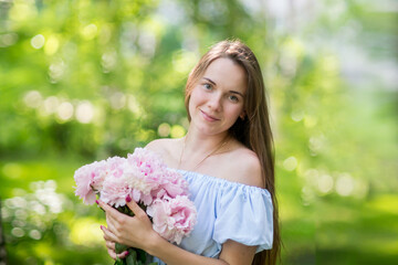 Fototapeta premium Young woman smiling behind pink peony flower