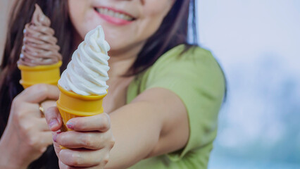 Asian young woman showing vanilla and chocolate ice cream and eating deliciously in summer with have fun and good mood.