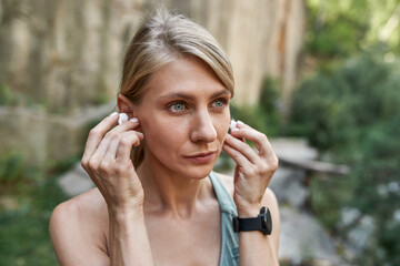 Sports woman put wireless earphones before run