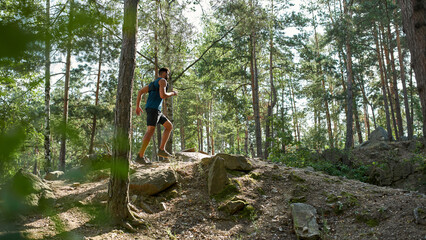 Side view of sportsman jogging on hill in forest