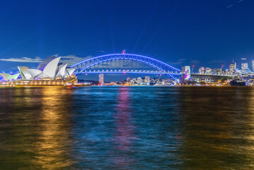 Colourful Light show at night on Sydney Harbour NSW Australia. The bridge illuminated with lasers and neon coloured lights 