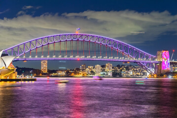 Colourful Light show at night on Sydney Harbour NSW Australia. The bridge illuminated with lasers and neon coloured lights 