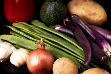 Variety of juicy vegetables on a black background. Vegetarian food