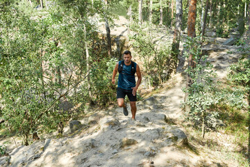 Young caucasian sportsman run up on hill in forest