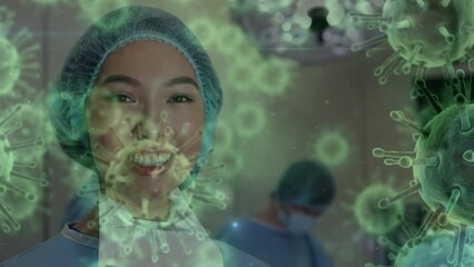 Animation of covid 19 cells over smiling biracial female surgeon in operating theatre - Powered by Adobe