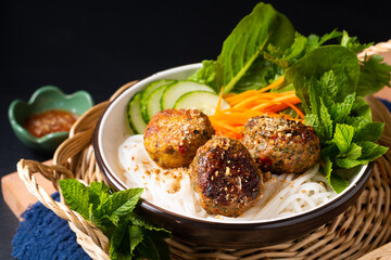 Food concept Bun Cha Vietnamese rice noodles and Meatballs with vegetables and herbs on black background with copy space
