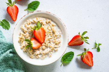 Oatmeal porridge with strawberry on white background. Healthy breakfast. Top view.