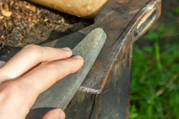 Manual sharpening of an axe. Grinding stone in the hands of the master.
