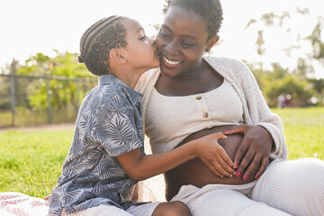 African pregnant woman enjoy tender moment with son at city park - Mother and child love