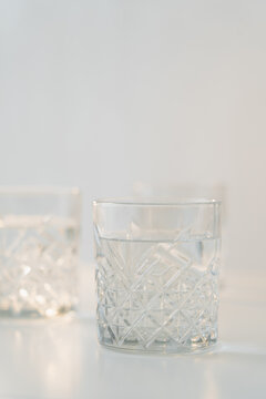 glass with faceted pattern and pure water on grey blurred background.