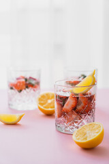 tonic water with lemon and strawberries on blurred background with white copy space.